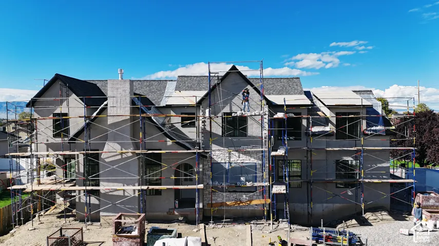 Two-story residence featuring a multi-gabled roofline, stone veneer accents, an exterior chimney, and large windows
