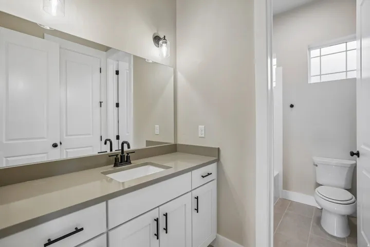 Bathroom featuring an expansive vanity with a light-toned countertop, integrated rectangular sink, and matte black fixtures
