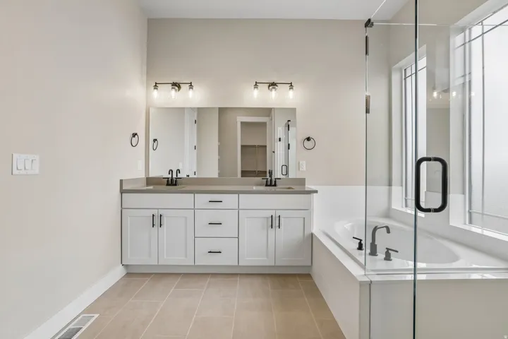Bathroom featuring a dual vanity with white cabinetry and dark hardware, set against a light countertop