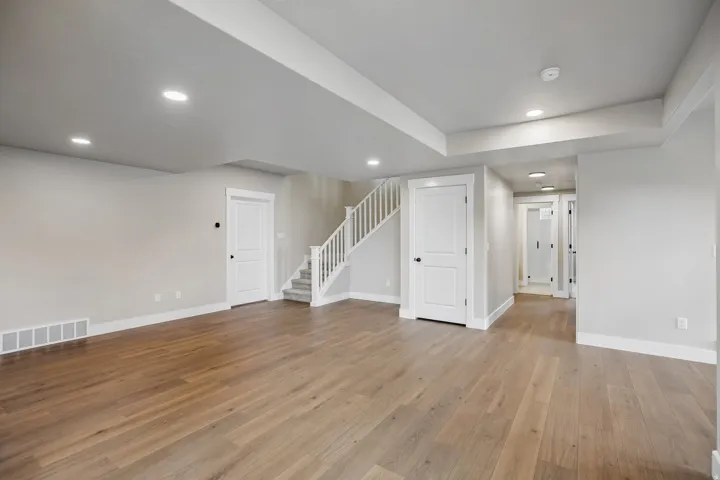 Spacious lower-level living area featuring wood-finish flooring and recessed lighting