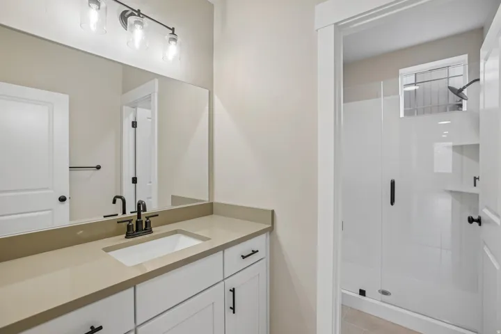 Bathroom featuring a vanity with an integrated rectangular sink, light-toned countertop, and white cabinetry with black hardware