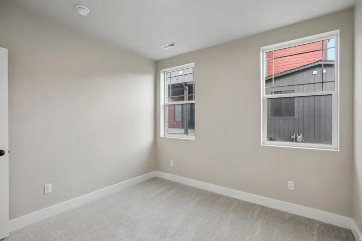 Neutral-toned interior room featuring light gray carpeting and white baseboards
