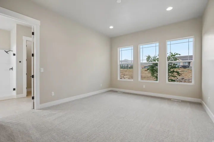 Spacious interior room with light neutral wall tones and plush grey carpeting