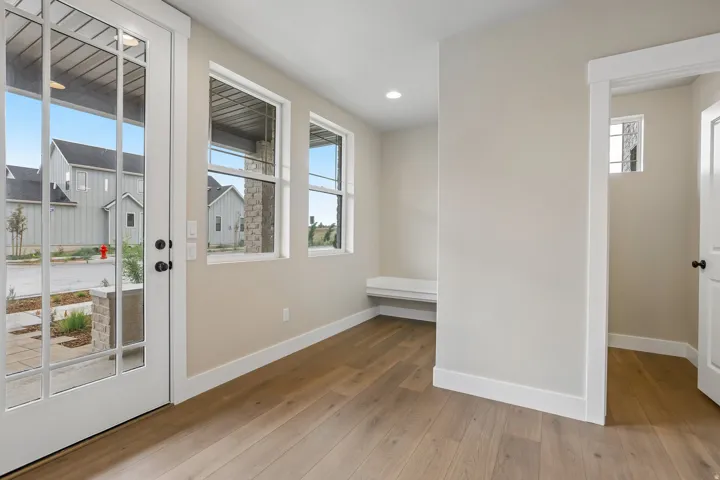 Entryway featuring a glass-paned front door, two casement windows, wood-finish flooring, a built-in bench, and recessed lighting