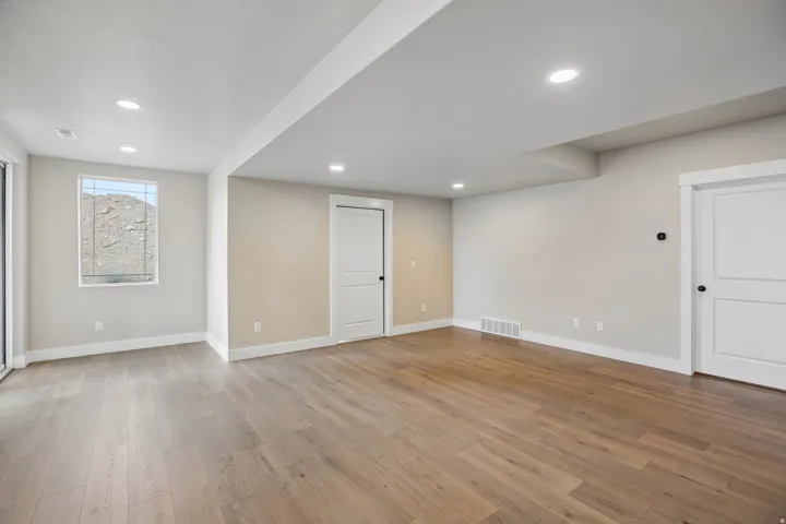 Spacious room featuring wood-finish flooring, recessed lighting, and a neutral color palette