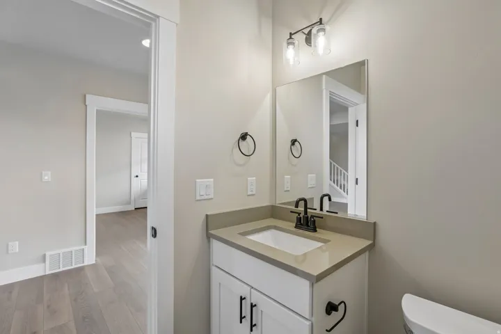 Bathroom vanity featuring a light-toned countertop, integrated sink, and matte black faucet