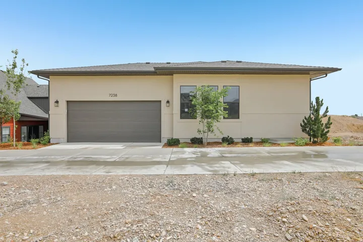 Contemporary stucco exterior featuring a two-car garage, multiple windows, and a paved driveway