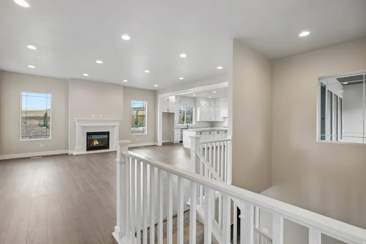 Open-concept living area featuring wood-finish flooring, a white mantel fireplace, and recessed lighting