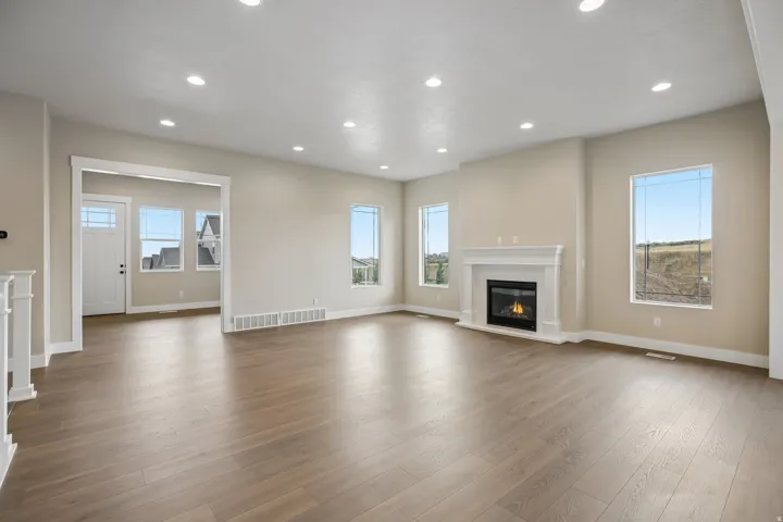 Spacious living area featuring wood-finish flooring, recessed lighting, and a white mantel fireplace