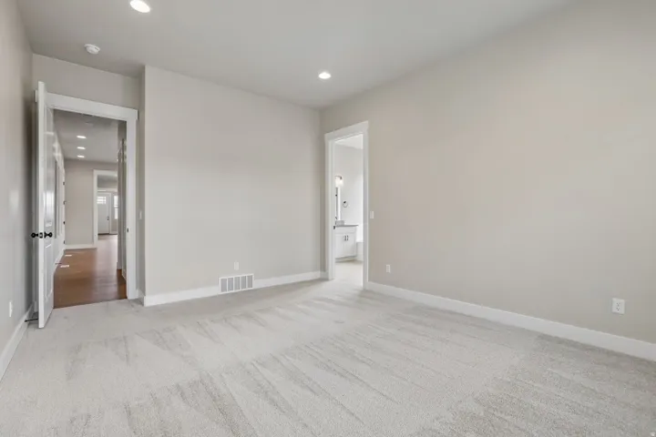 Spacious room featuring light gray carpet flooring, recessed ceiling lighting, and neutral wall paint