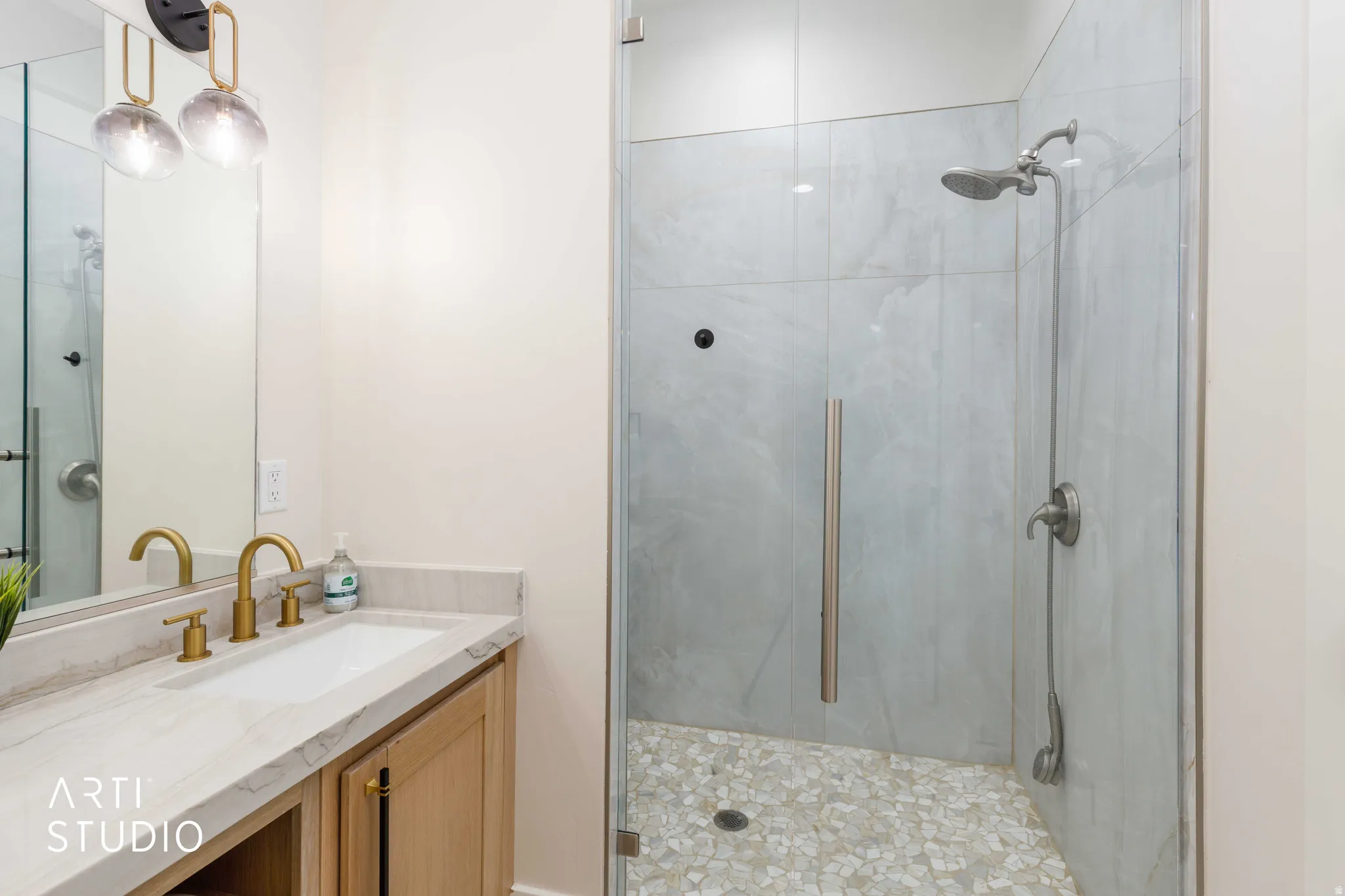 Glass-enclosed shower featuring large format tile surround and pebble tile flooring