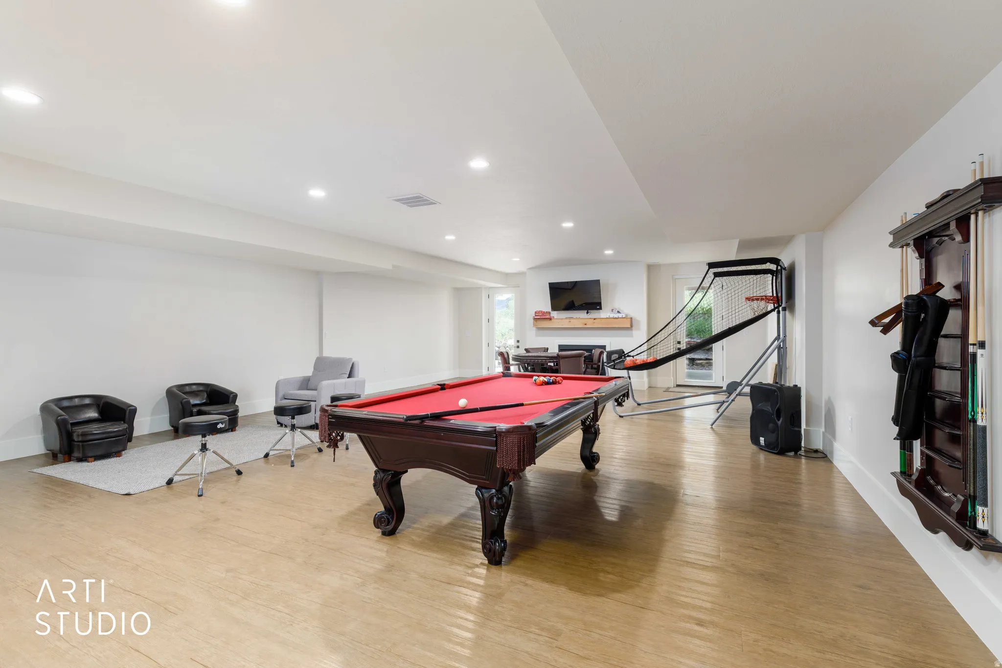 Spacious entertainment room featuring light wood-finish flooring, recessed lighting, and white walls