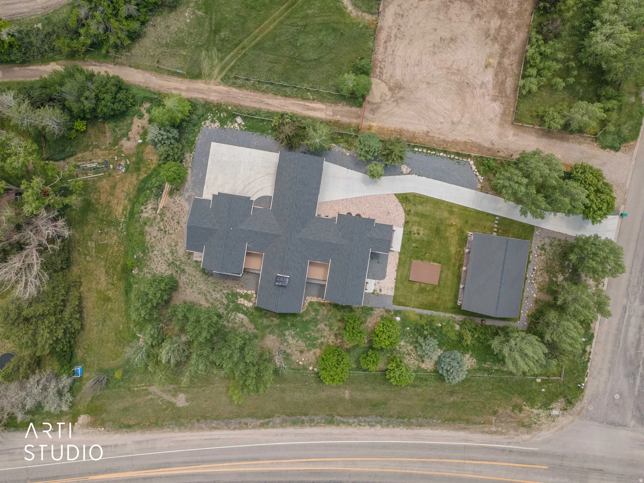 Expansive property featuring a multi-gabled main residence, a detached auxiliary building, and extensive paved driveways