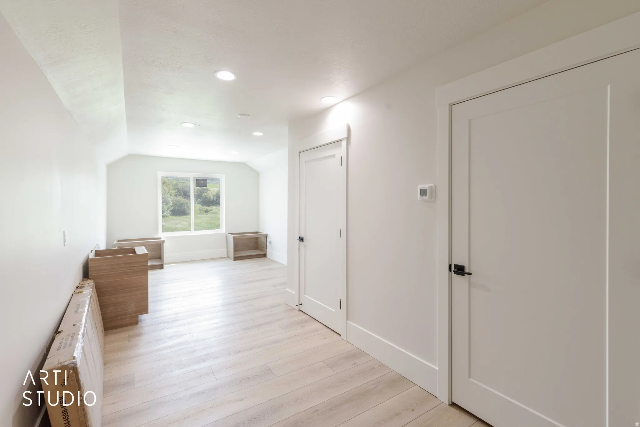 Spacious room featuring light wood-finish flooring, recessed lighting, and a window providing natural illumination
