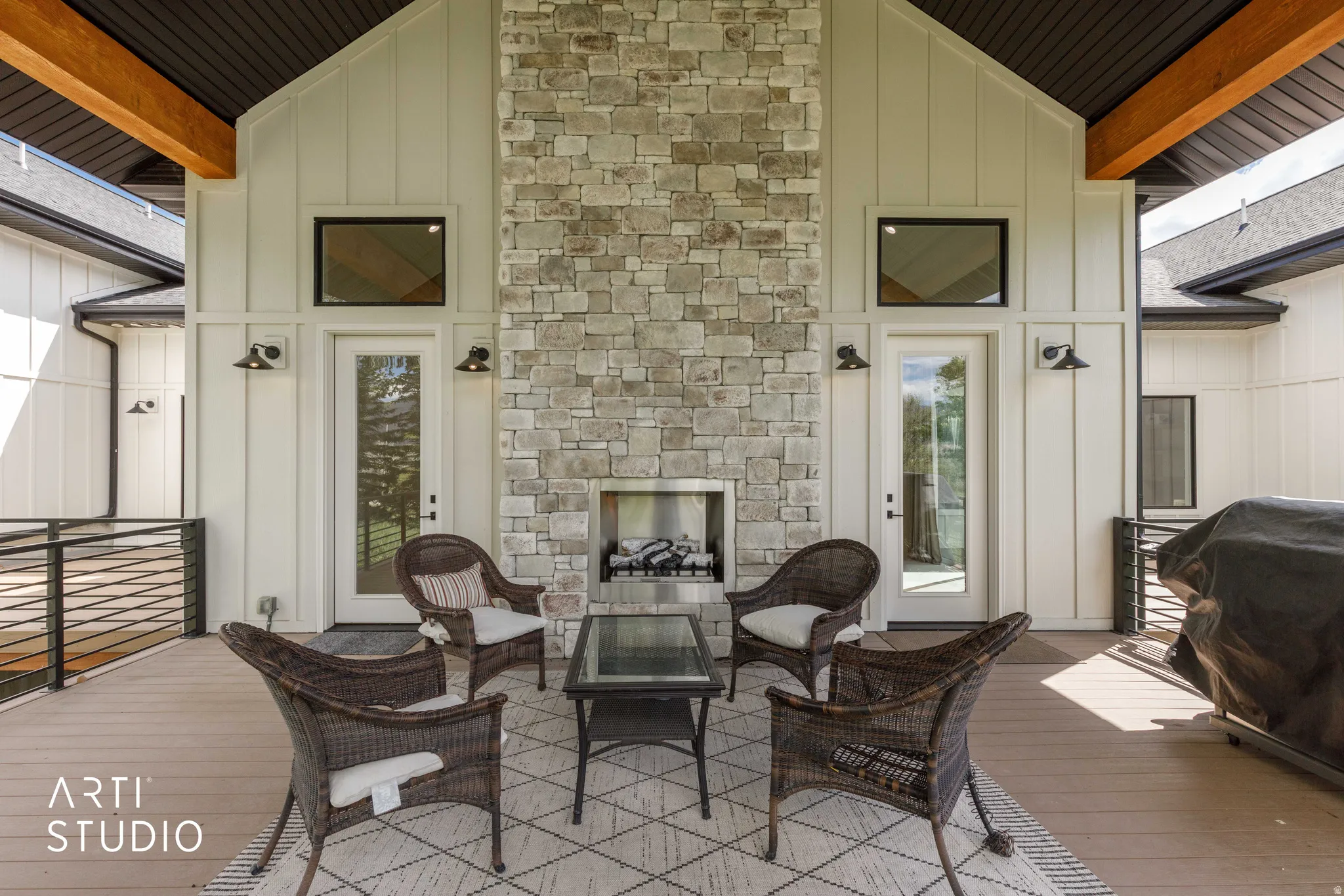 Expansive covered patio featuring a stone fireplace with a built-in firebox, exposed wood beams, and composite decking