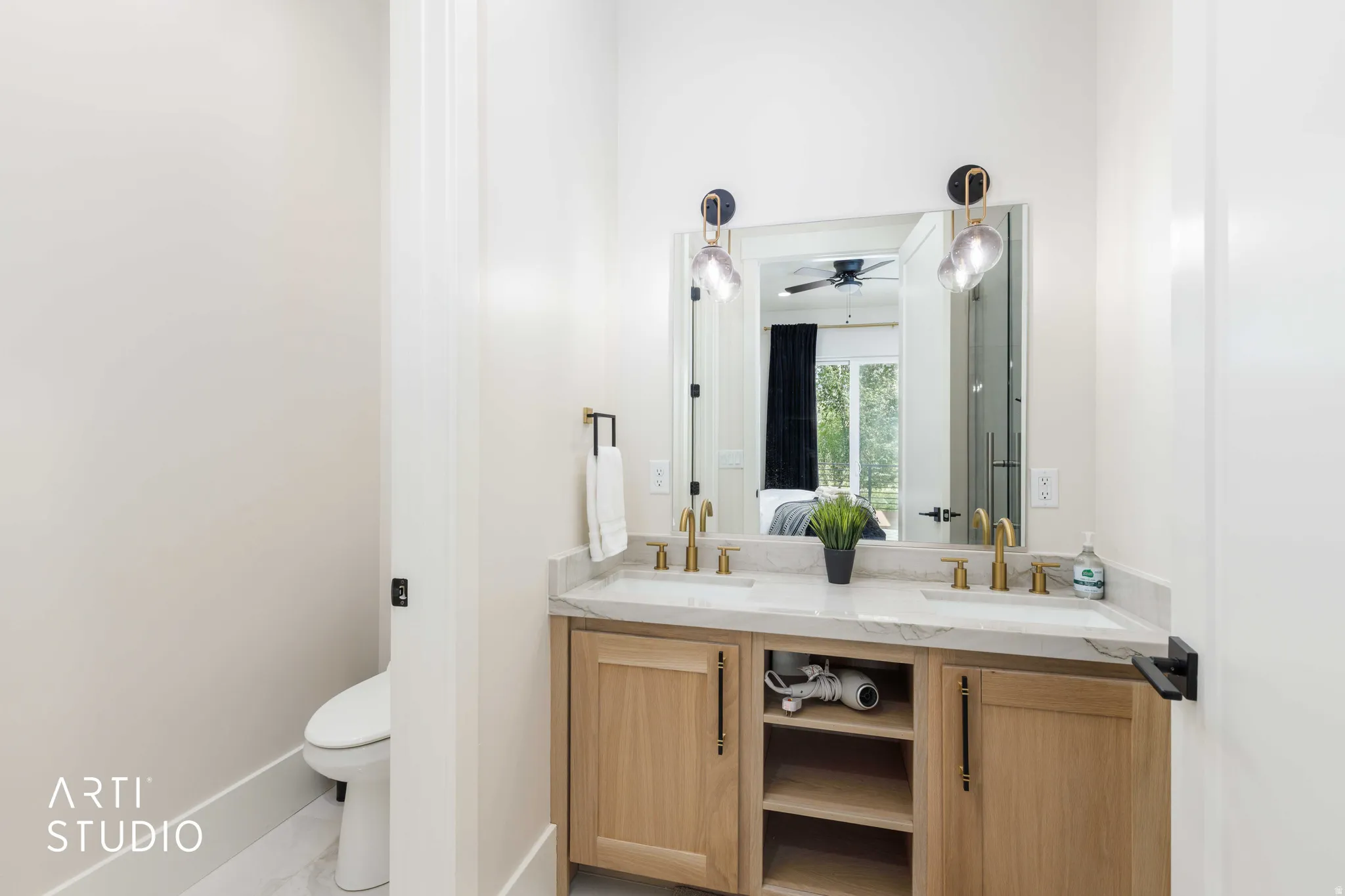 Dual vanity with wood-finish cabinetry, light-toned countertop, and gold-finish fixtures