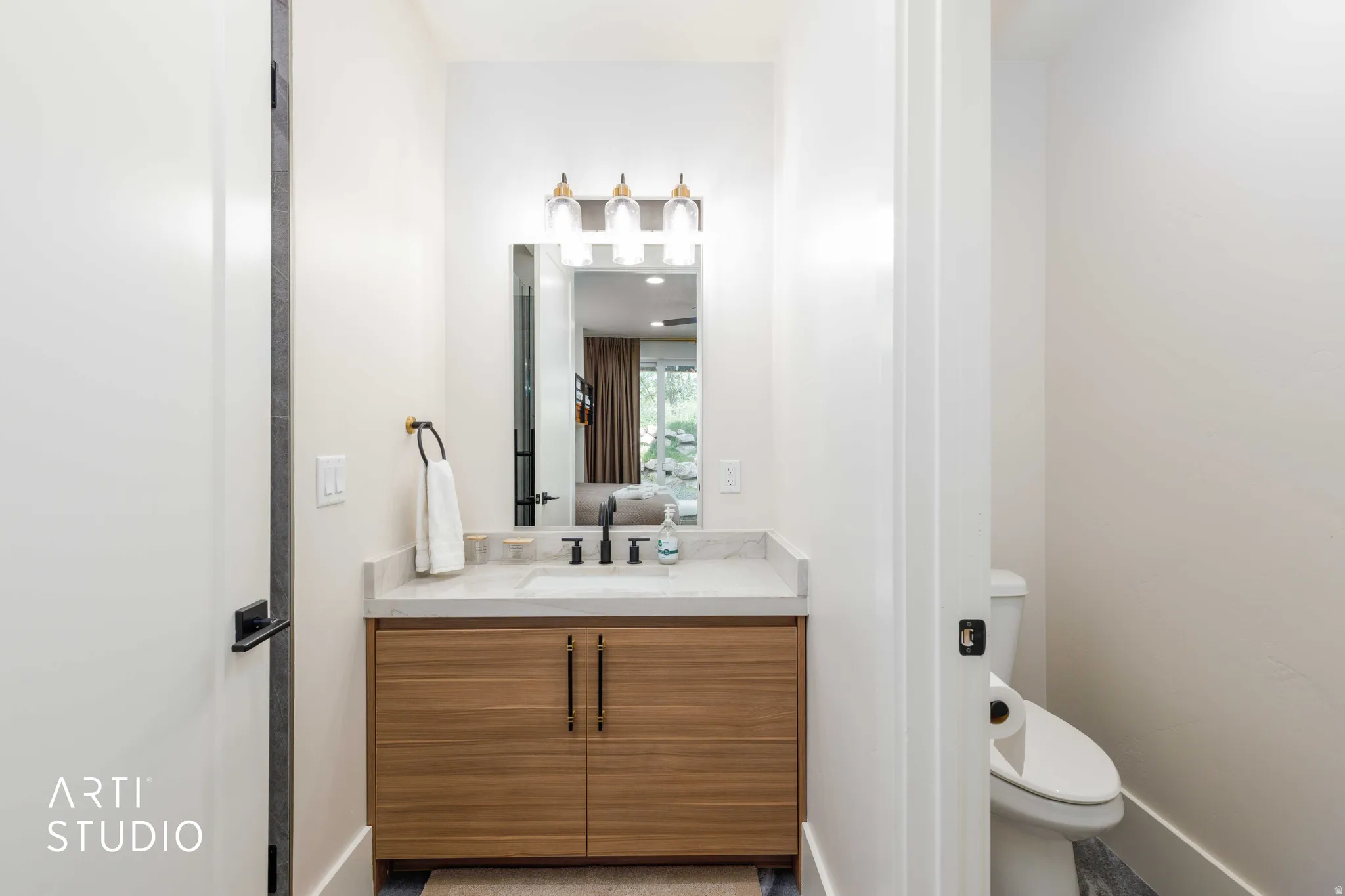 Bathroom featuring a wood-finish vanity with dual doors, a stone countertop, an integrated sink with a matte black faucet, and a rectangular mirror