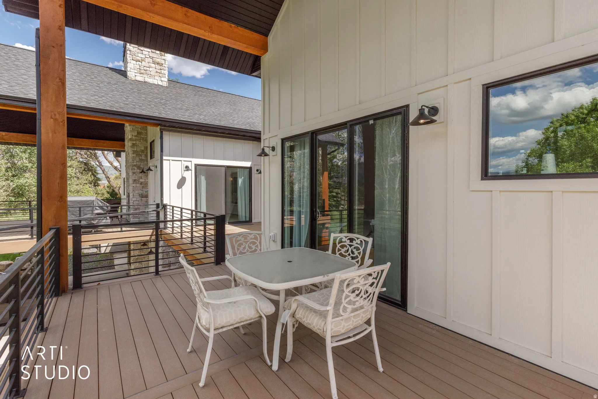 Spacious outdoor deck featuring composite decking, black metal railings, and a board and batten exterior