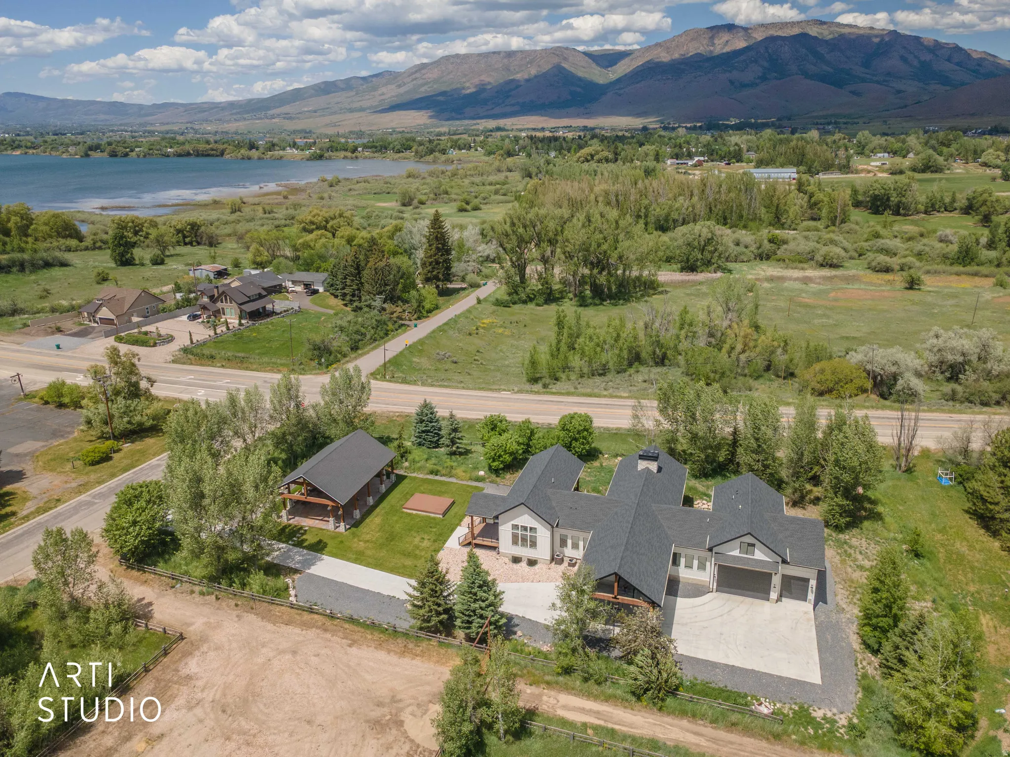 Modern multi-structure property featuring a main residence with an attached three-car garage, a separate barn-style outbuilding, and a gravel driveway