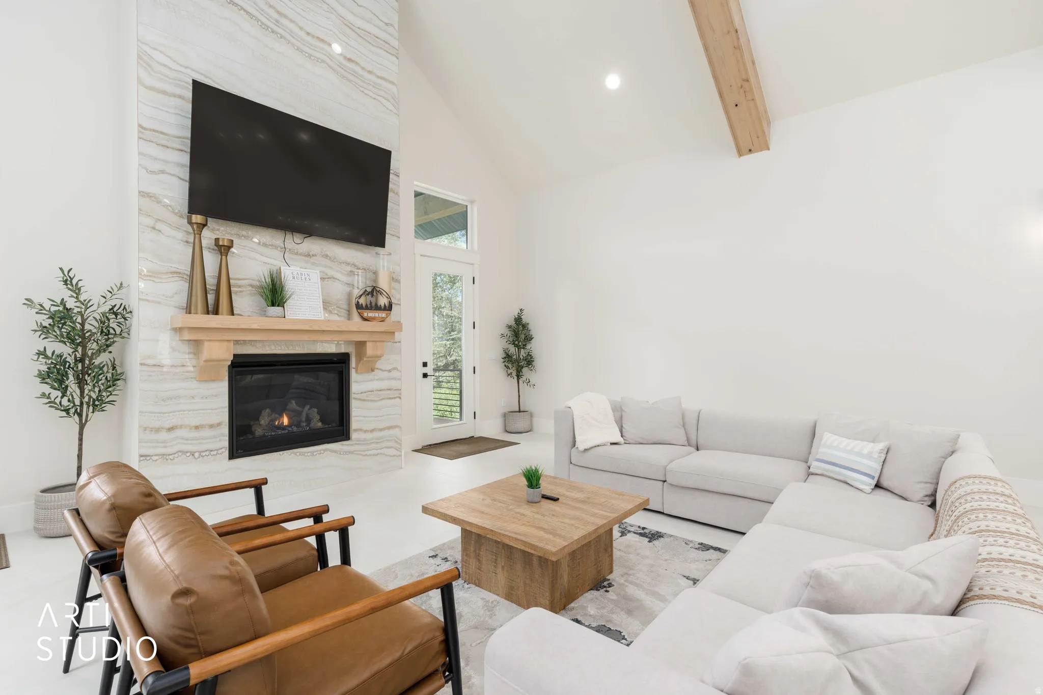 Vaulted ceiling living space featuring a floor-to-ceiling fireplace with stone-finish surround and wood mantel
