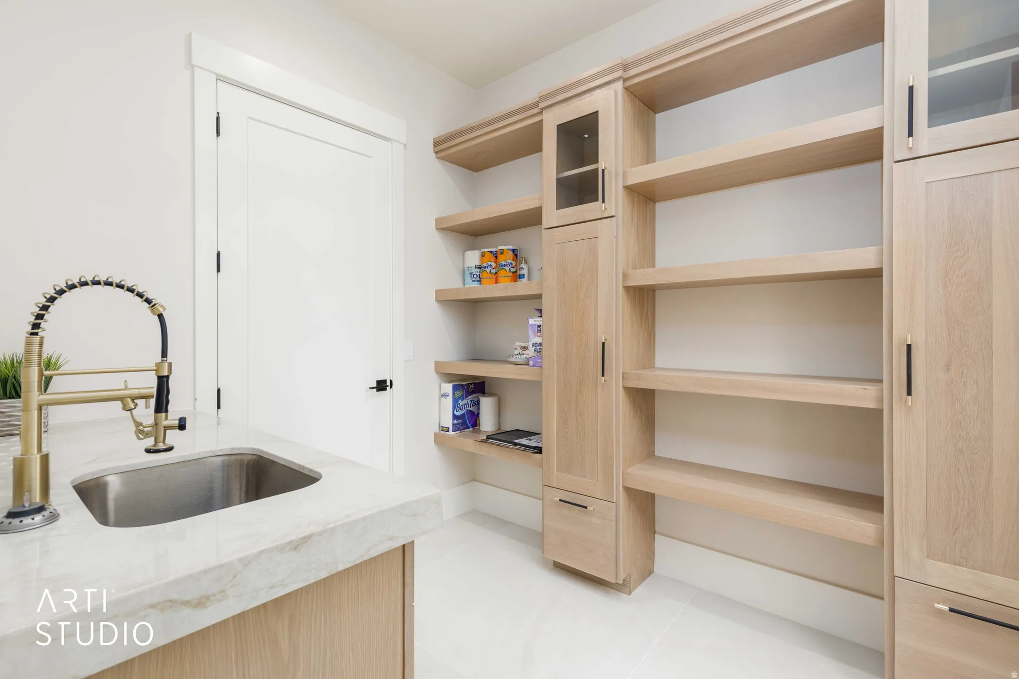 Utility area featuring a stainless steel sink, gold-finish pull-down faucet, and light-tone countertop