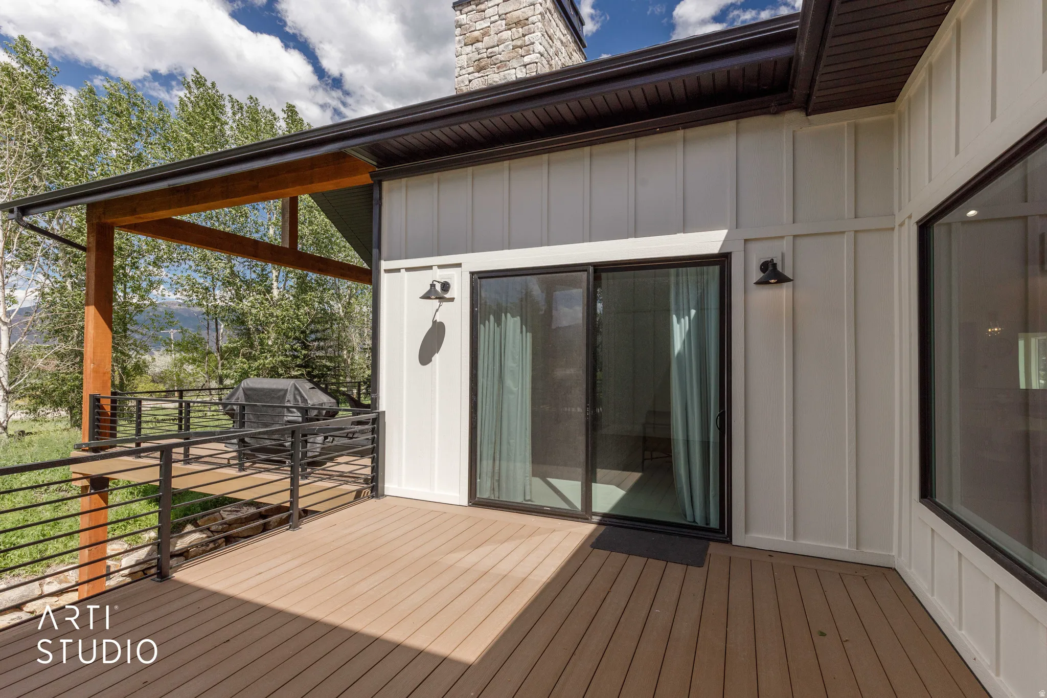 Expansive deck featuring composite wood-finish flooring, black metal railings, and a covered section with wood beams