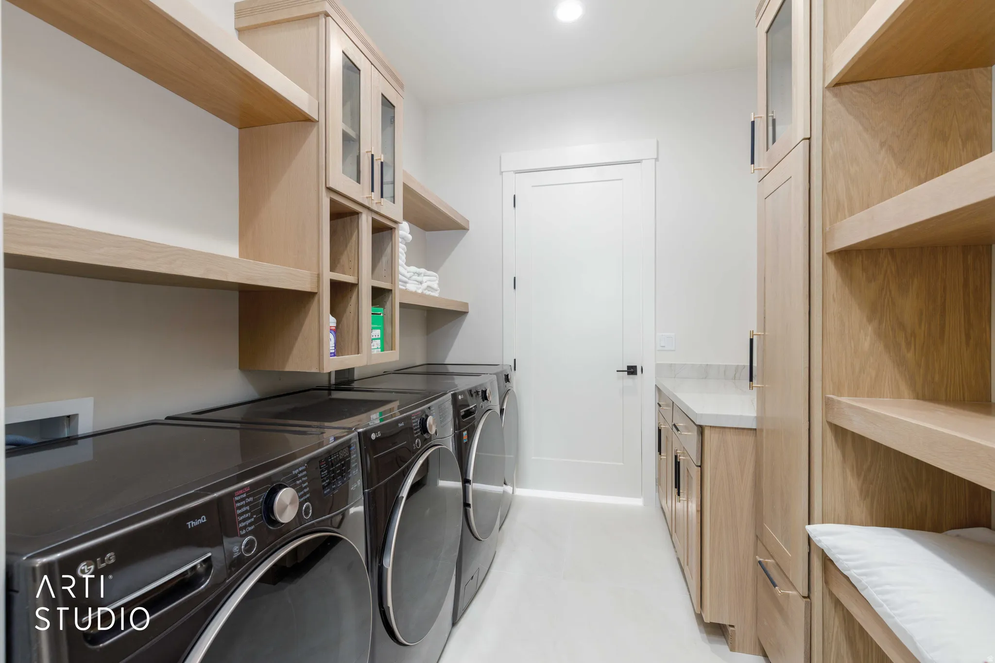 Laundry room featuring light wood-finish cabinetry, open shelving, and a built-in counter