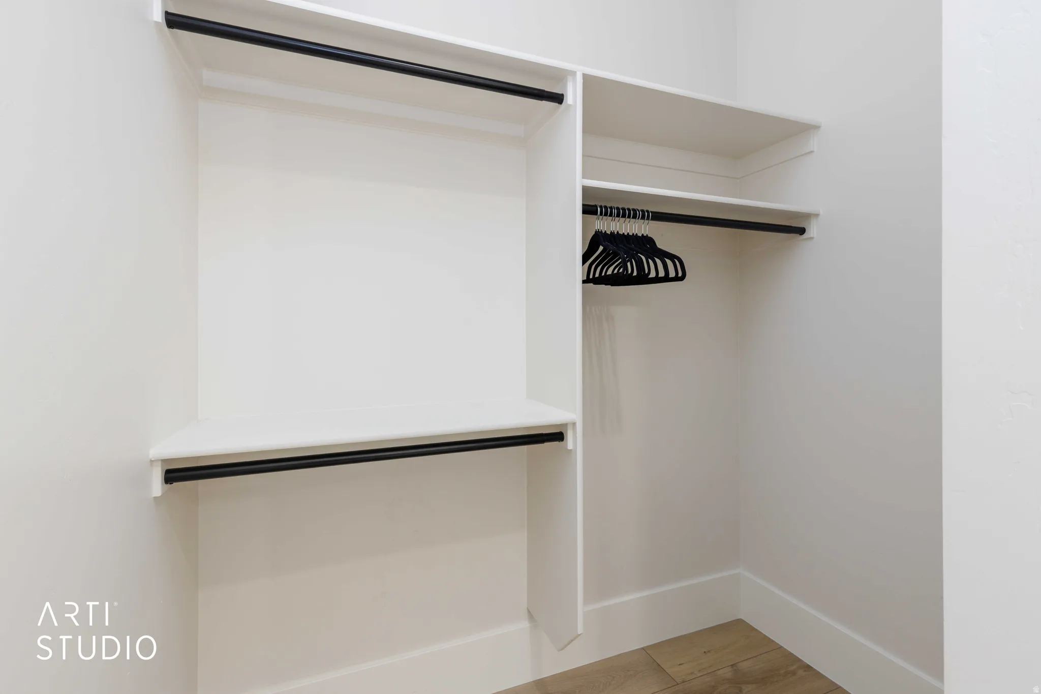 Built-in closet system featuring white shelving and black hanging rods