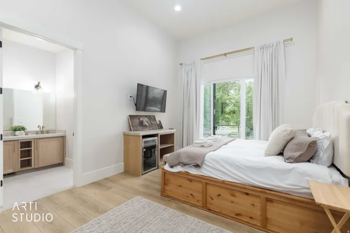Spacious room with wood-finish flooring, a large sliding glass door, high ceilings, and a built-in beverage refrigerator