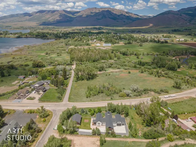 Aerial perspective showcasing a sprawling landscape with a prominent body of water, distant mountains, and extensive green fields