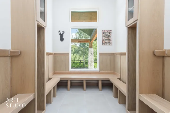 Built-in wood-finish benches and storage cubbies with upper cabinetry frame a large picture window, offering abundant natural light