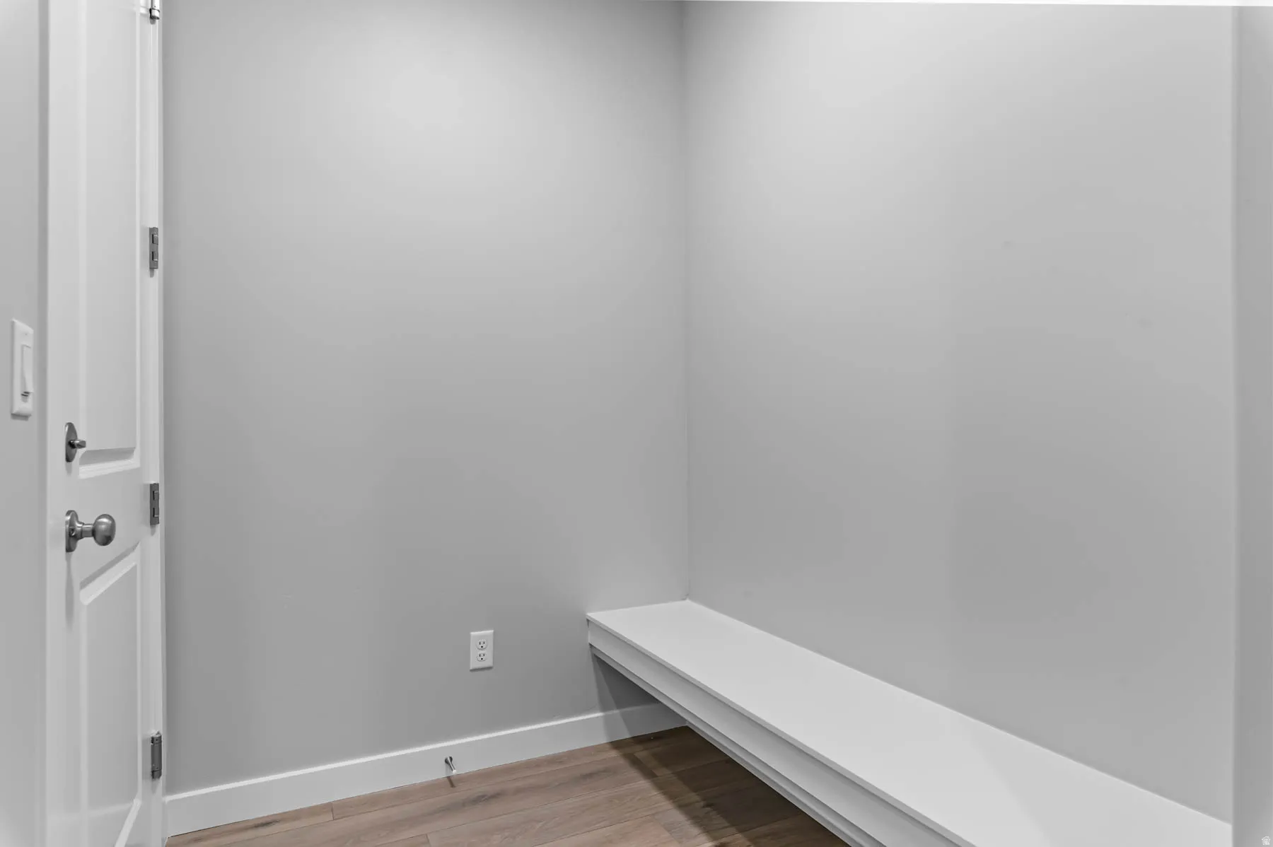 Corner alcove featuring a built-in bench, wood-finish flooring, and crisp white trim