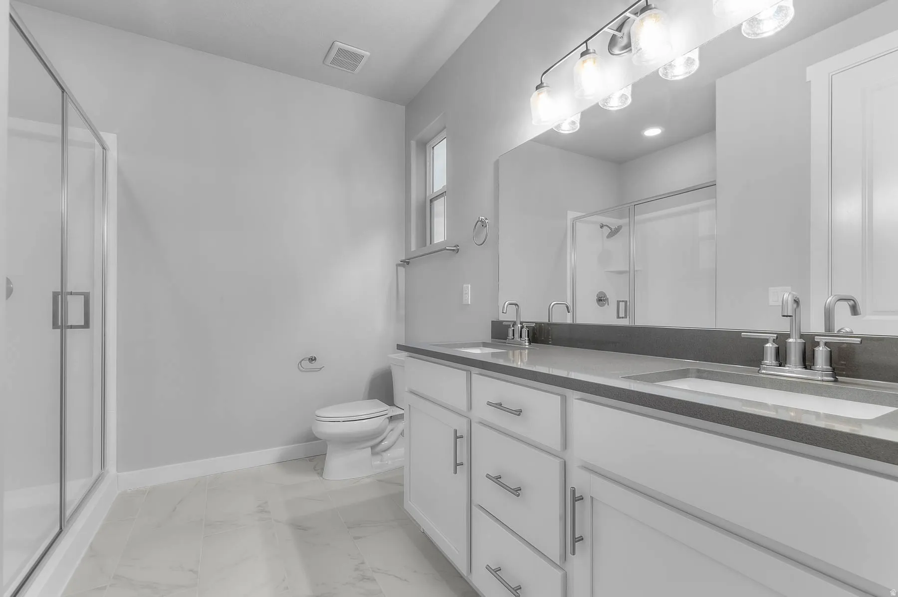 Bathroom featuring a double vanity with white cabinetry, dark countertops, and undermount sinks