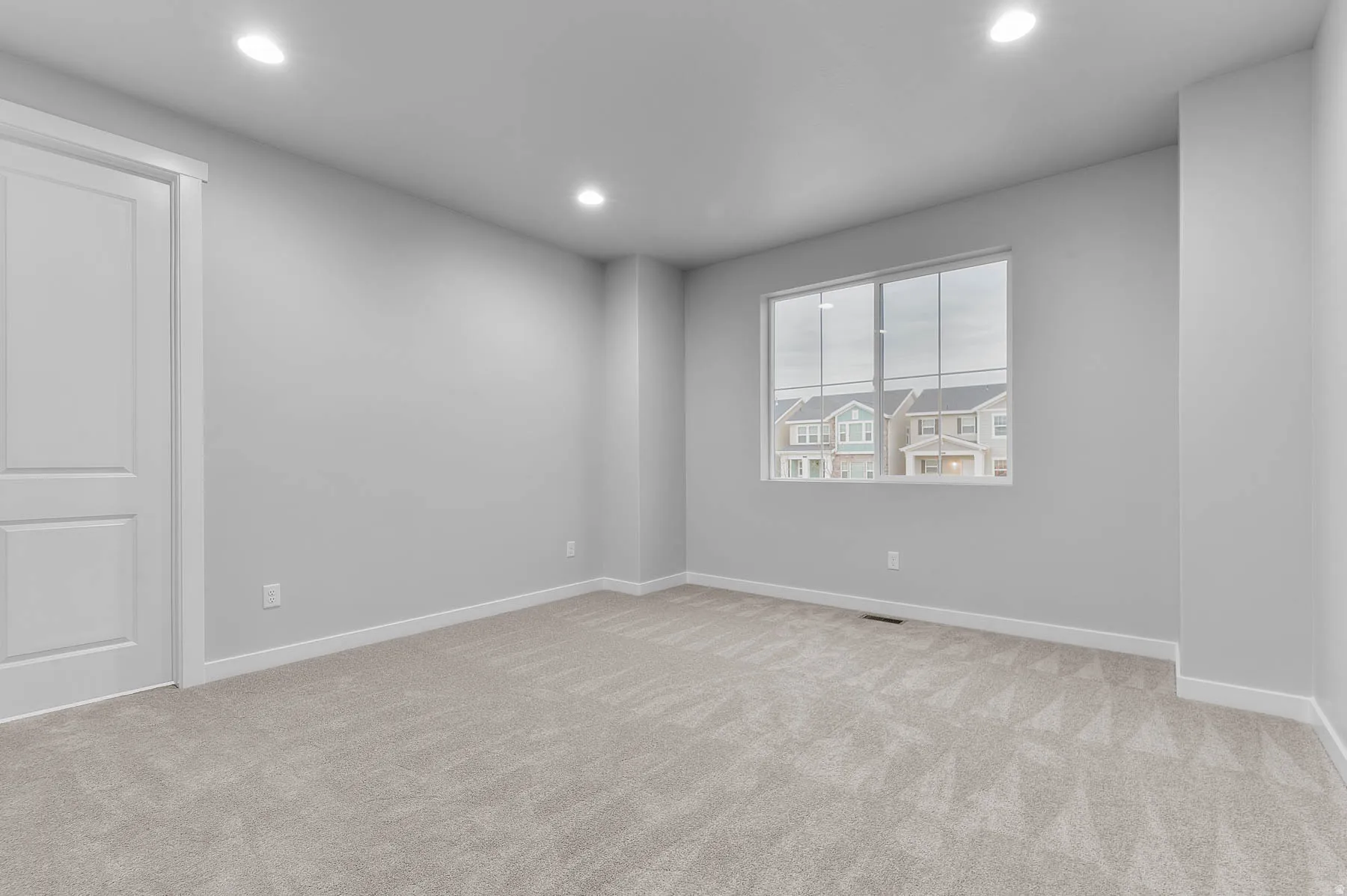 Neutral gray walls with recessed lighting and a multi-pane window
