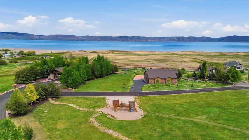 Expansive waterfront property featuring a substantial body of water, distant mountain range, and lush green landscaping