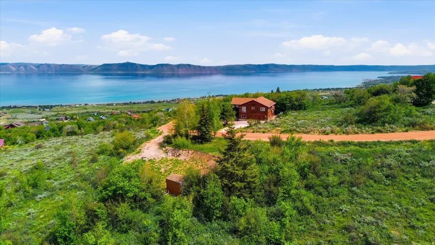 Wood-sided residence situated on an elevated lot with a lake backdrop