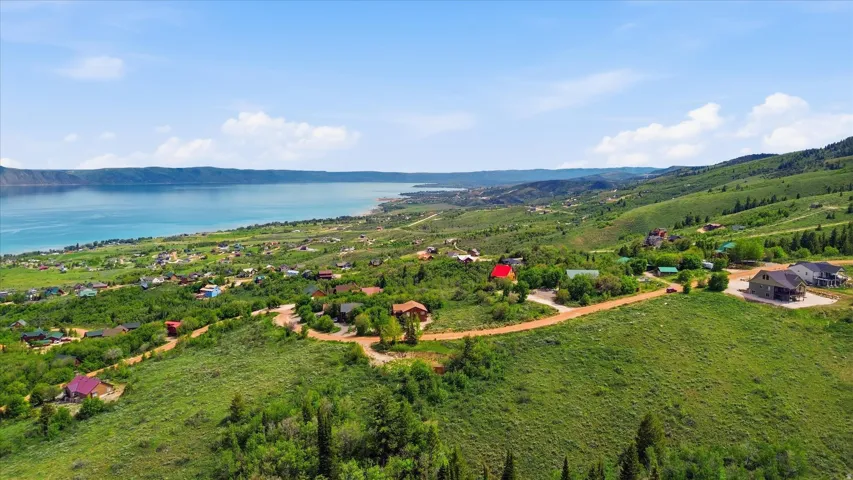 Expansive natural landscape featuring rolling green hills and a large body of water