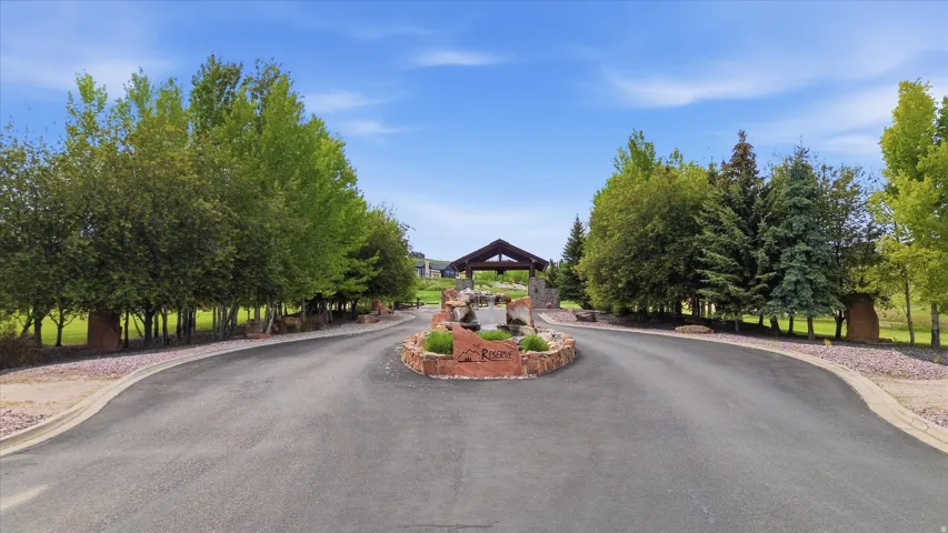 Paved entry drive with a central stone island and mature trees
