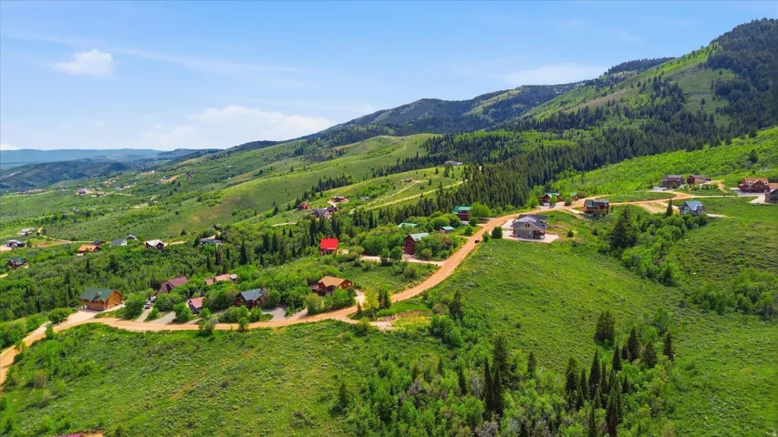 Expansive mountain landscape featuring verdant hillsides and scattered residential properties