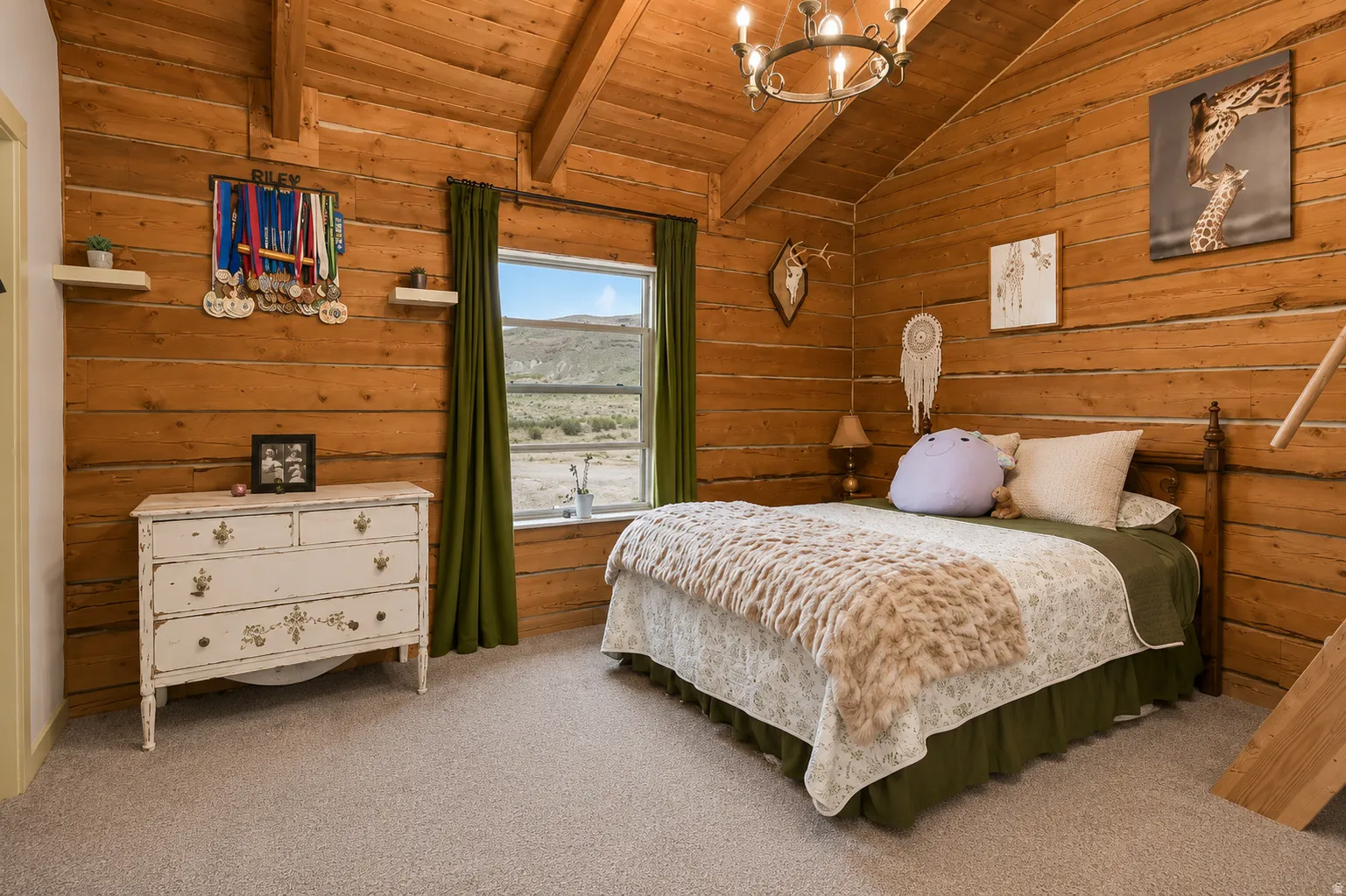 Room featuring light wood-finish log walls, a vaulted ceiling with exposed beams, and a window providing natural light