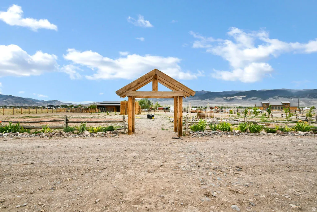 Outdoor property featuring a rustic timber frame gateway, split rail fencing, and cultivated garden beds