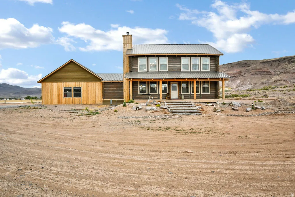 Two-story residence featuring a metal roof, log siding, and a covered front porch with exposed timber columns