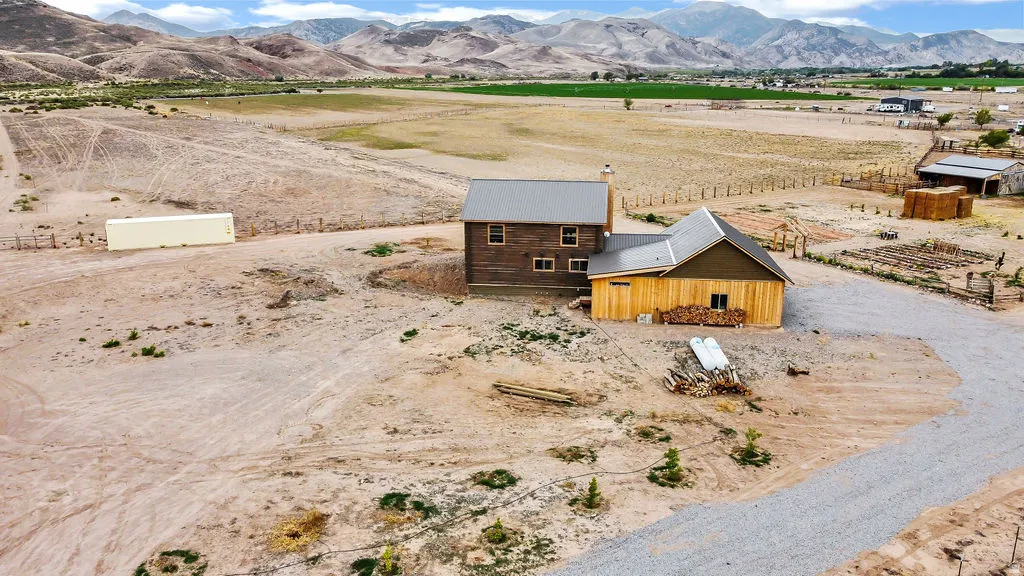 Rural property featuring a two-story residence with a metal roof and a detached outbuilding with natural wood siding
