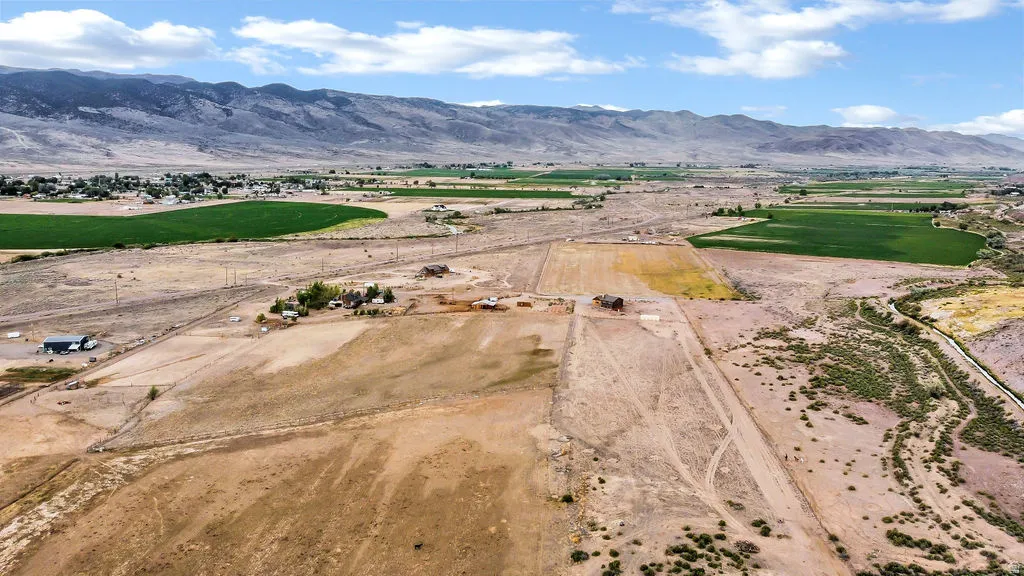 Expansive land parcel featuring open fields, distant mountain backdrop, and multiple existing structures