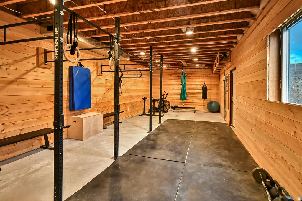 Lower-level recreation space featuring wood-paneled walls and exposed ceiling beams