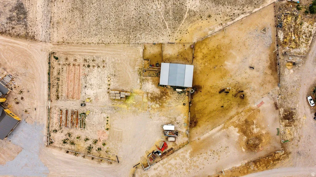 Expansive property featuring an agricultural area with tilled garden beds, a large outbuilding with a metal roof, and fenced perimeter