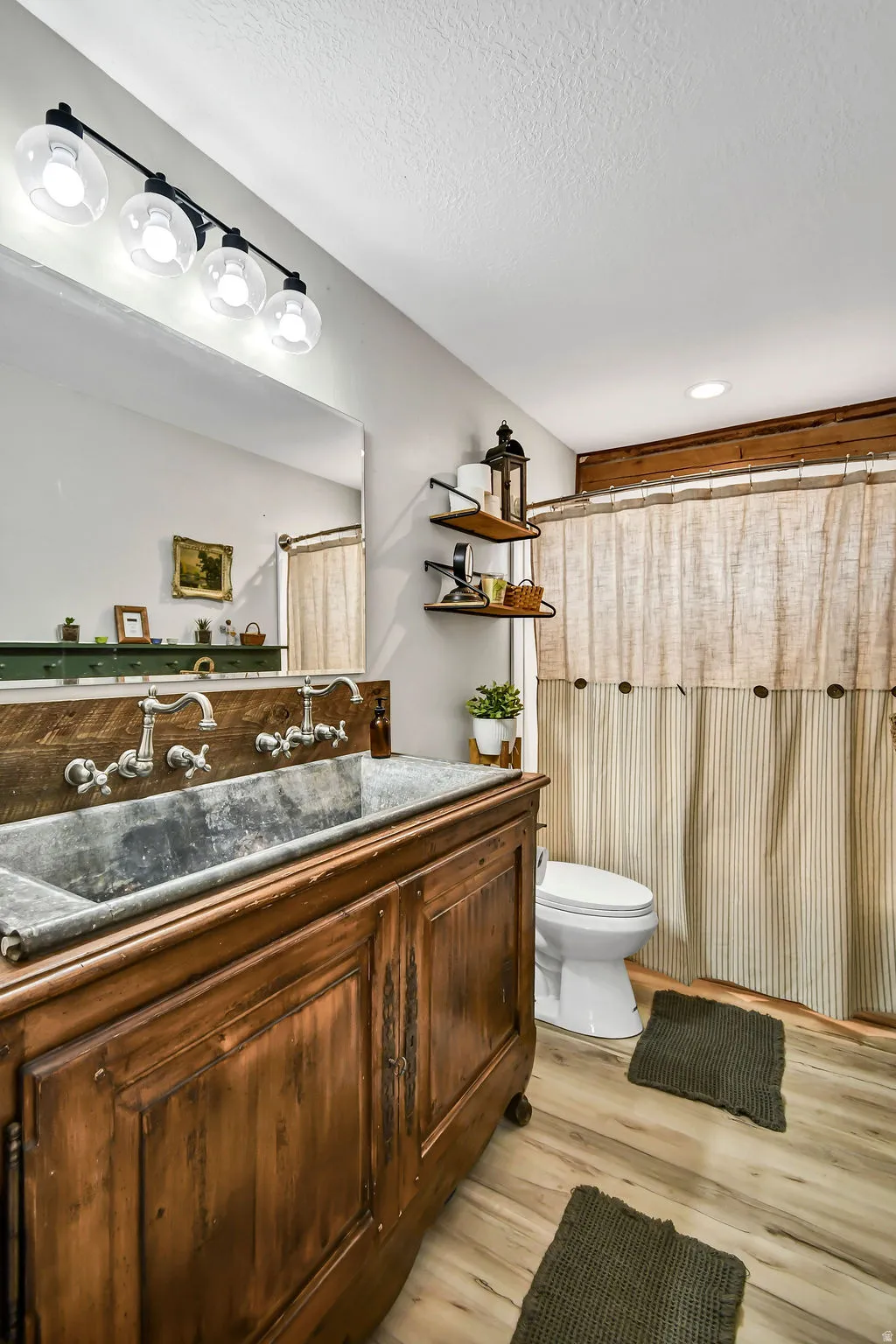 Distressed wood vanity featuring a trough sink, wall-mounted faucets, and a paneled wood backsplash