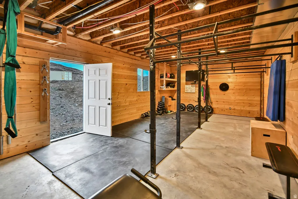 Finished basement space featuring exposed wood ceiling joists and wood-paneled walls