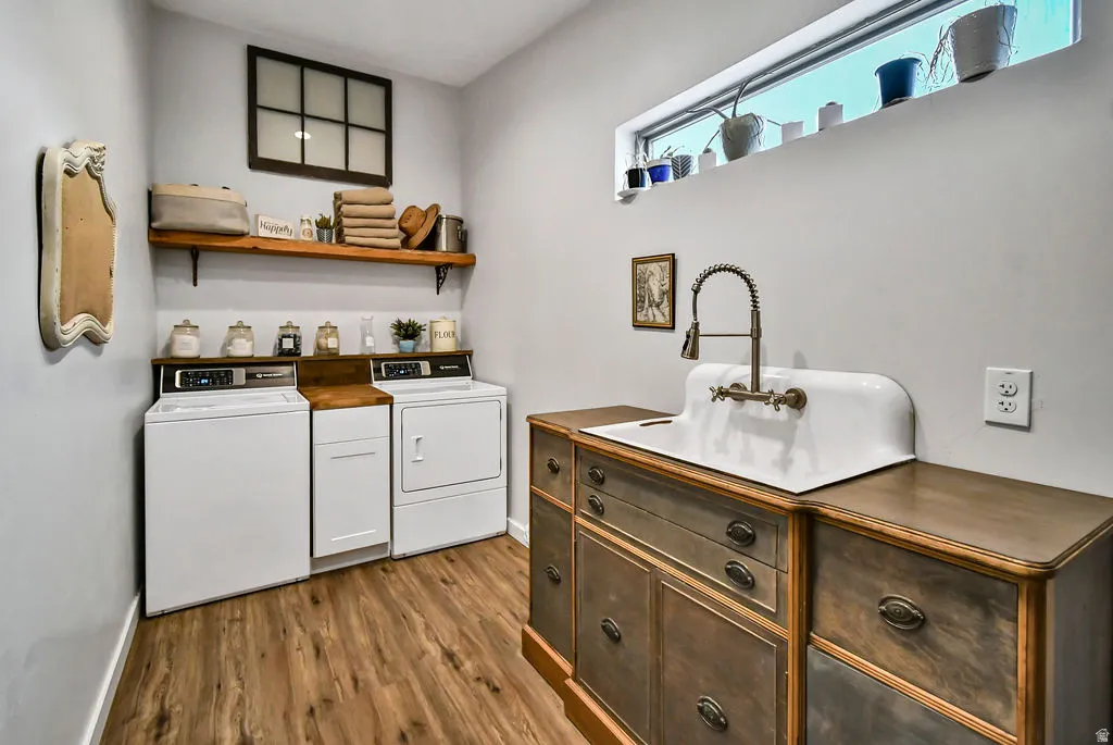 Laundry room featuring wood-finish flooring, a white porcelain utility sink with a high-arc faucet, and wood shelving