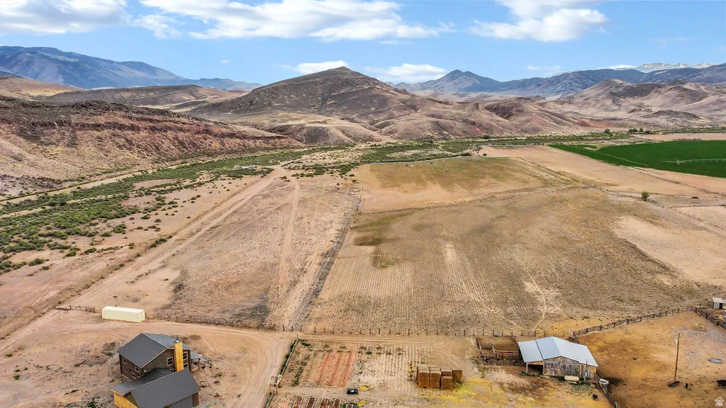 Expansive rural property featuring multiple structures, open fields, and a mountainous backdrop